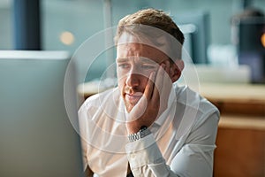 Why does this day feel so long. a bored businessman staring blankly at his computer screen.