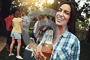 Why dont you grab a beer and join us. Portrait of a young woman enjoying a party with friends outdoors.