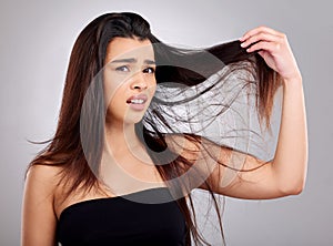 Why is it so knotty. Studio portrait of an attractive young woman having a bad hair day against a grey background.