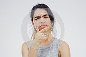 Why are you even thinking about it. Studio shot of a young woman looking thoughtful against a gray background.