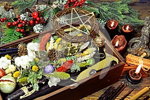 Wicca concept with box of presents, black candles, pentagram, magic healing herbs, conifer