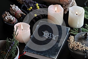 Wiccan witch altar with a hand made old looking book grimoire with triple moon symbol