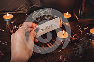 Wiccan witch holding a piece of paper with words So mote it be written on it, and burning it at her altar. Witch casting a spell photo