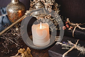 Wiccan witch putting out a white candle flame with antique brass gold colored wick snuffer.