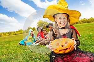 Wicked girl in witch dress with Halloween pumpkin