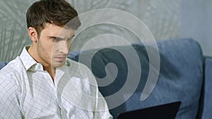 Wicked man hitting laptop indoors. Angry guy using computer inside.