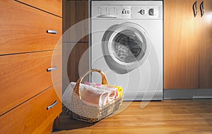 Wicker Basket with Clean Towels on the Floor near the Washing Machine with Laundry. House Interior Laundry Room. Wood Interior