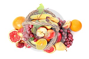 Wicker basket with different fruits on white background, top view