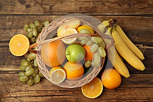 Wicker basket with different fruits on wooden table, flat lay