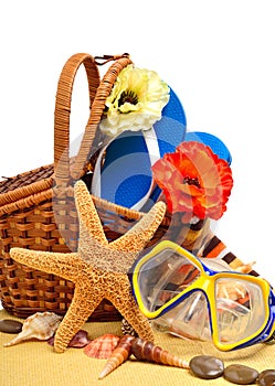 Wicker basket, flip-flops, fishstar, goggles on the towel photo