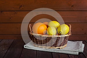 Wicker basket with fresh ripe oranges and lemons on aged wooden table