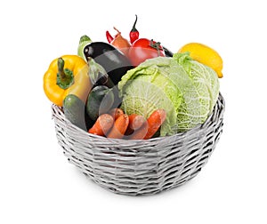 Wicker basket with fresh ripe vegetables and fruit on white background