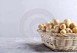 Wicker basket full of new spring potatoes.Raw new potatoes in the container made of stiff fibers on the grey surface against grey