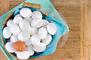 Wicker basket full of white eggs with one brown