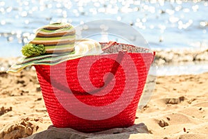 Wicker basket handbag bag and hat on summer beach.