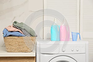 Wicker basket with laundry, detergents and washing machine in bathroom