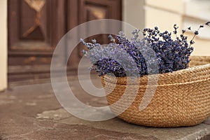 Wicker basket with lavender flowers on cement floor. Space for text