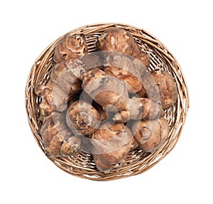 Wicker basket with many Jerusalem artichokes isolated on white, top view