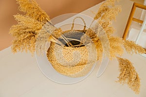 A wicker basket with panicles of reeds stands on the floor in the interior