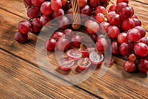 Wicker basket with red ripe grapes on wooden table
