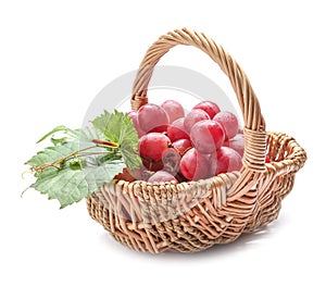 Wicker basket with ripe grapes on white background