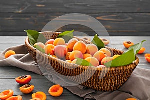 Wicker basket with ripe sweet apricots on wooden table