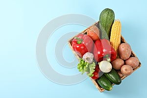 Wicker basket with vegetables on blue background