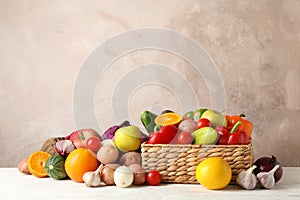 Wicker basket, vegetables and fruits on white wooden background