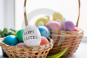 Wicker baskets with bright colorful eggs and with text Happy Easter and flower