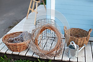 Wicker baskets next to garden tools, watering can and dried spikelets, pampas grass against wall of a blue house. Gardening concep