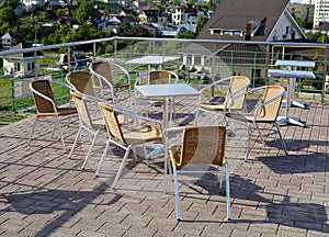 Wicker chairs with metal legs and racks are in an open cafe area