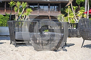 Wicker chairs and table in empty beach cafe next to sea. Close up. Thailand