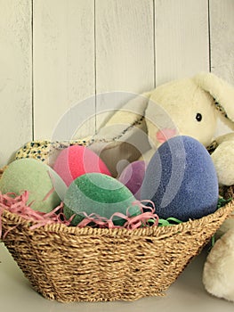 wicker easter basket with colorful bright eggs, and white bunny with long ears