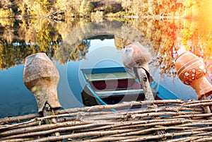 Wicker fence with jugs in the background of the lake with a boat