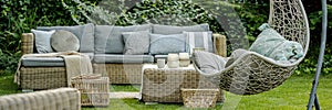 Wicker garden furniture with grey pillows in beautif