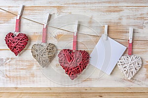 Wicker hearts made of straw hanging on brown rope on wooden background. Valentine day or love concept. Copy space