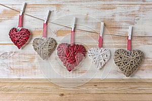 Wicker hearts made of straw hanging on brown rope on wooden background. Valentine day or love concept. Copy space