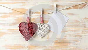 Wicker hearts made of straw hanging on brown rope on wooden background. Valentine day or love concept. Copy space