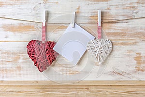 Wicker hearts made of straw hanging on brown rope on wooden background. Valentine day or love concept. Copy space