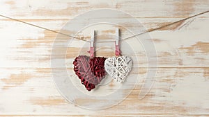 Wicker hearts made of straw hanging on brown rope on wooden background. Valentine day or love concept. Copy space