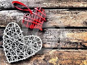 A wicker hearts a wooden background. Two red braided heart with hanging loop. White big heart. Two lovers. Valentine