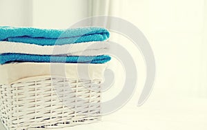 Wicker laundry basket with clean folded towels on the bed