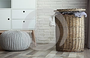 Wicker laundry basket with dirty clothes at home