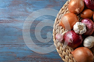 Wicker mat with garlic and onions on color wooden table