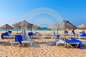 Wicker parasols and beach beds at coast with sea