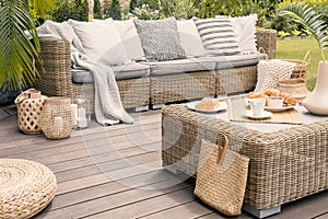 Wicker patio set with beige cushions standing on a wooden board