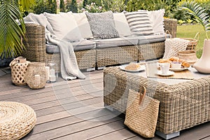 Wicker patio set with beige cushions standing on a wooden board photo