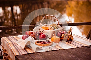 Wicker picnic basket with different products on rock dark brown wooden old board table