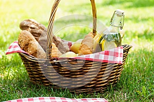 Wicker picnic basket with food and drink in a park