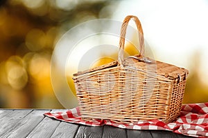 Wicker picnic basket on wooden table, space for text